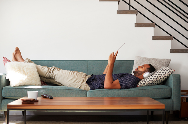 man looking at iPad on green couch