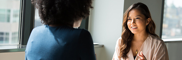 two women conversing across table