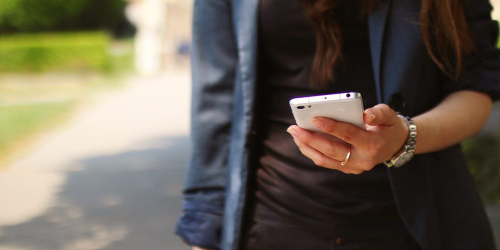 girl texting outside wearing blue jacket