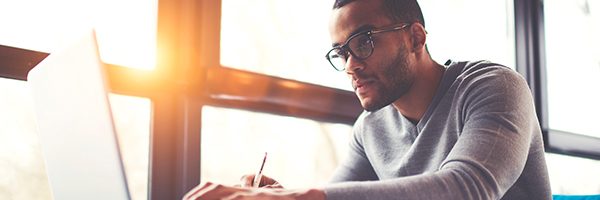 man looking at laptop with sun shining through window