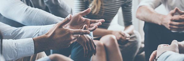 man with open hands sitting in group circle