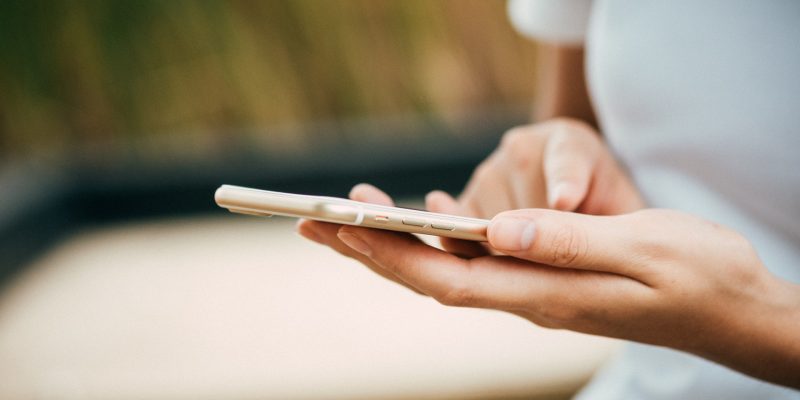 girl in white shirt texting on gold iPhone