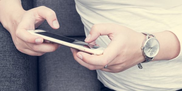 woman on gray couch texting